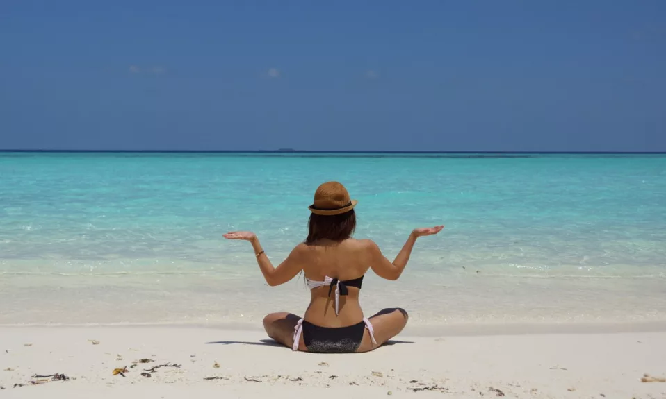 Femme méditant plage tropicale sereine.